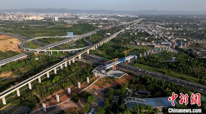 航拍正在建設(shè)的跨越成都繞城高速公路連續(xù)梁施工現(xiàn)場，旁邊依次為已運(yùn)營的成渝高速鐵路和機(jī)場高速公路?！⒅铱?攝