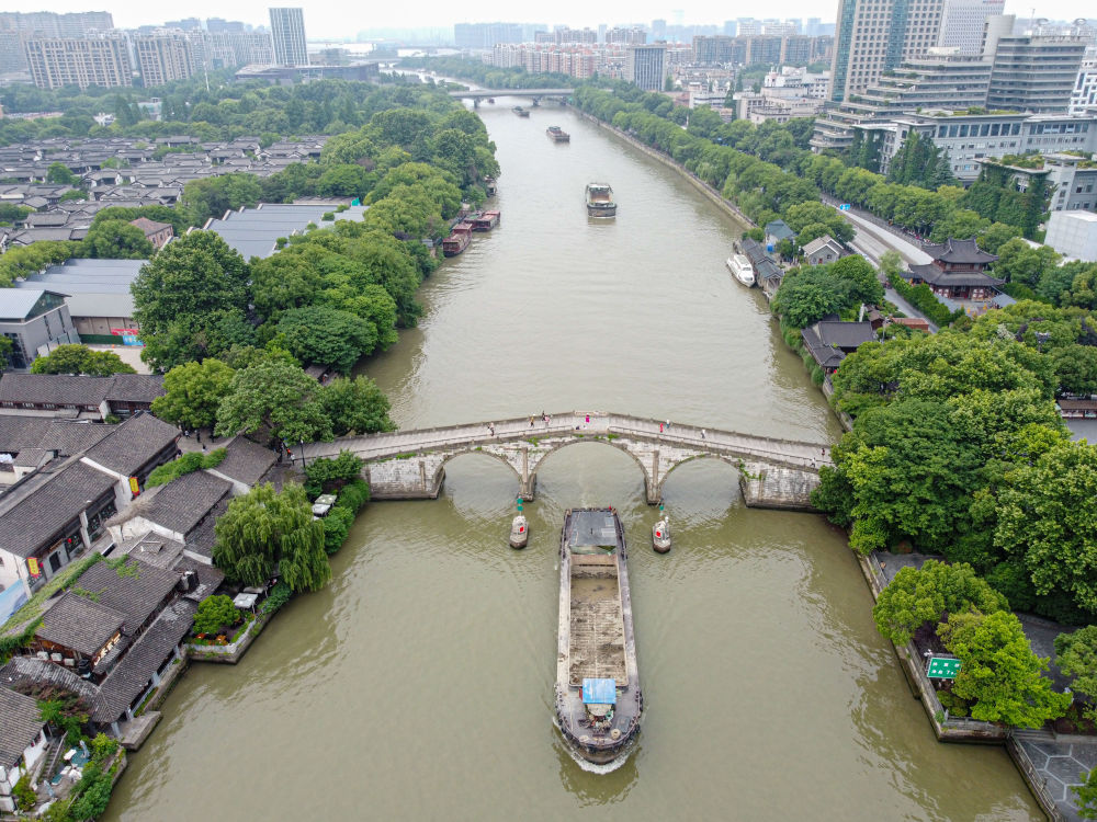 5月27日，一艘貨船駛過(guò)京杭大運(yùn)河南端標(biāo)志建筑杭州拱宸橋。(無(wú)人機(jī)照片)新華社記者江漢 攝