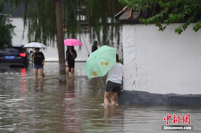 7月31日，市民行走在雨中的北京房山區(qū)瓦窯頭村。北京市氣象臺當(dāng)日10時發(fā)布分區(qū)域暴雨紅色預(yù)警信號。北京市水文總站發(fā)布洪水紅色預(yù)警，預(yù)計當(dāng)日12時至14時，房山區(qū)大石河流域?qū)⒊霈F(xiàn)紅色預(yù)警標準洪水。<a target='_blank' href='/'><p  align=