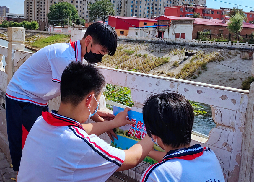 徐水小學(xué)學(xué)雷鋒志愿者在瀑河河邊張貼防溺水警示標(biāo)語(yǔ)。 徐水區(qū)委宣傳部供圖